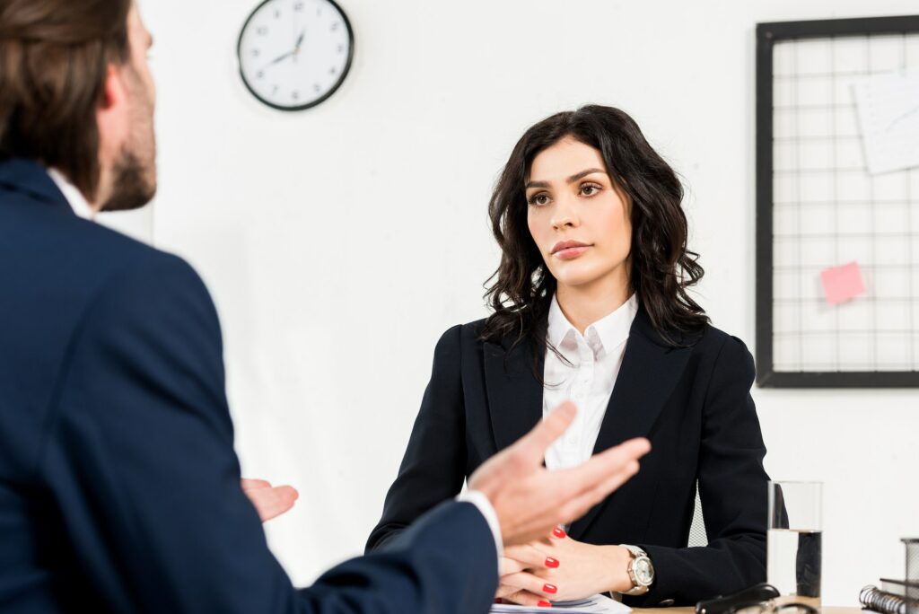 selective focus of attractive recruiter looking at man gesturing during job interview